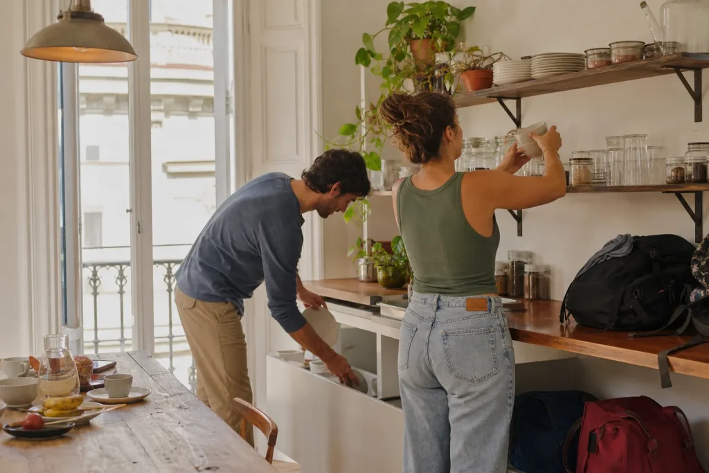 Viaggiatori riordinano insieme la cucina di un appartamento condiviso